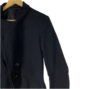 May include: A black long-sleeved jacket with a high collar and two buttons. The jacket has a slightly fitted silhouette.