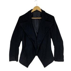 May include: A black blazer with a long, pointed collar and a draped front. The blazer has long sleeves and a fitted silhouette.