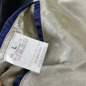 May include: White tag with black text that reads "RA L" and a red strikethrough of a symbol that looks like an iron. The tag also has a black and white symbol that looks like a washing machine. Below the symbol is a black and white symbol that looks like a dry clean symbol. Below the symbols is black text that reads "06-6543-6889" and "MADE IN CHINA".
