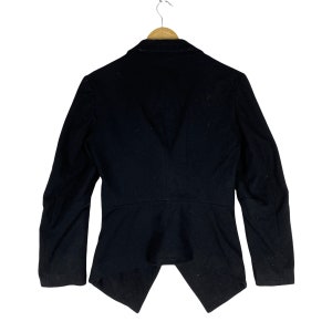 May include: A black blazer with a long, pointed back hem. The blazer has a classic collar and long sleeves.
