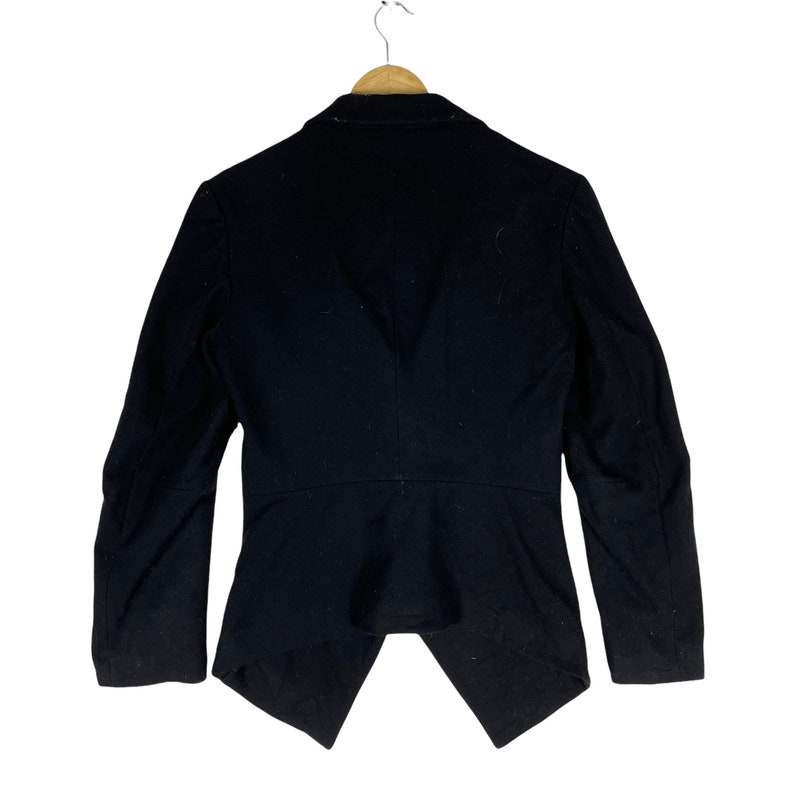 May include: A black blazer with a long, pointed back hem. The blazer has a classic collar and long sleeves.