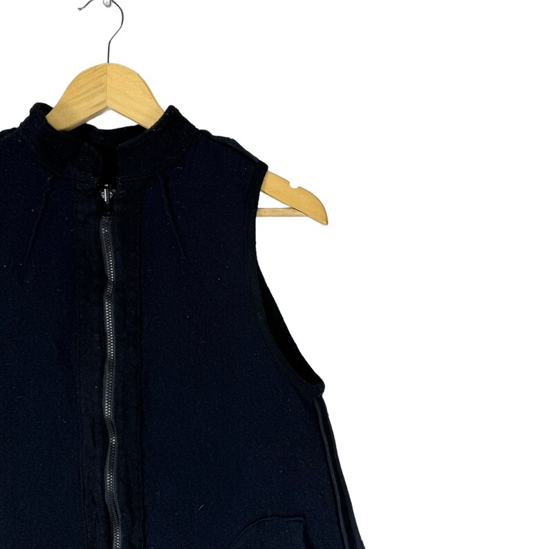 K&ouml;nnte beinhalten: Schwarze &auml;rmellose Steppweste mit Stehkragen und einer Tasche auf der Vorderseite.