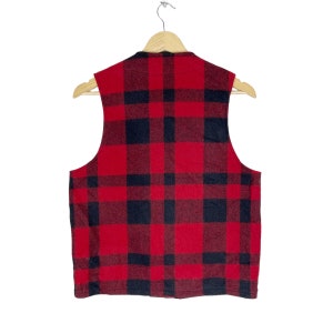 Op de afbeelding: Een rood en zwart geruit, mouwloos vest. Het vest is gemaakt van een zacht, pluche materiaal en heeft een klassiek, tijdloos ontwerp.