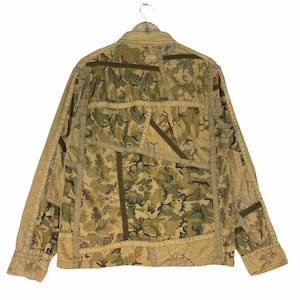 May include: A brown and green camouflage patterned jacket with a button-up front and long sleeves. The jacket is made of a patchwork of different fabrics and has a unique design.