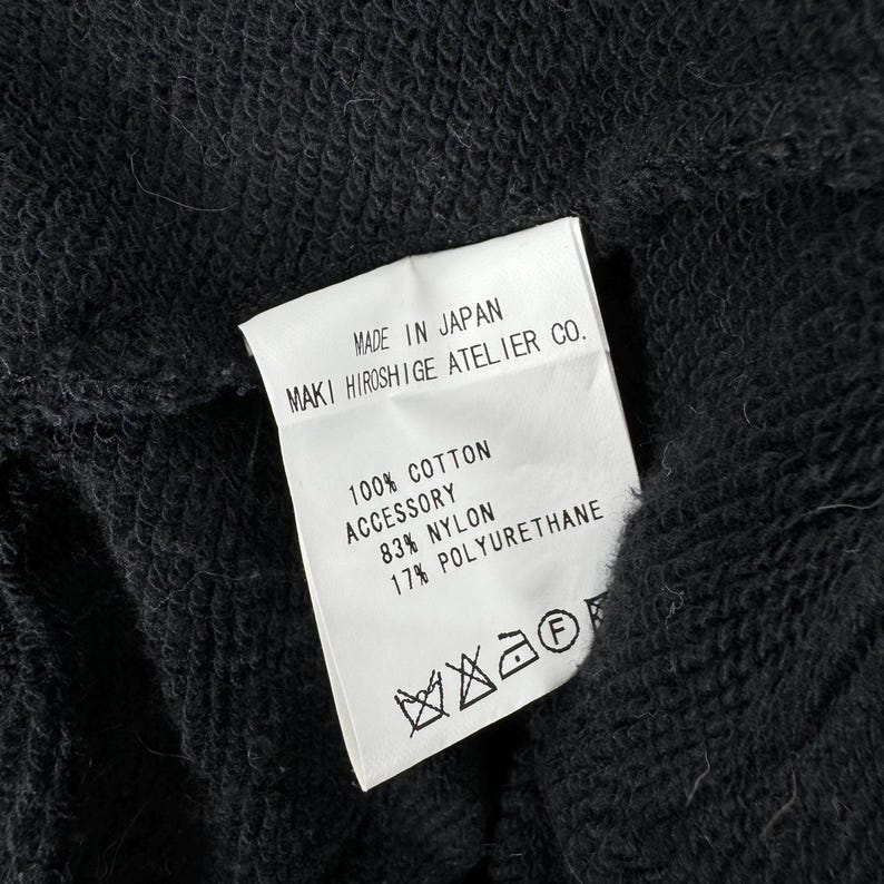 May include: White care label with black text that reads "MADE IN JAPAN MAKI HIROSHIGE ATELIER CO. 100% COTTON ACCESSORY 83% NYLON 17% POLYURETHANE". The label also has a black and white care symbol.