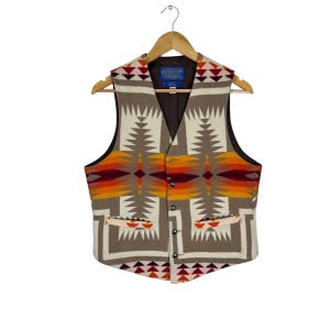 May include: A wool vest with a geometric pattern in shades of brown, cream, red, and orange. The vest has a V-neck, two front pockets, and a button-up closure. The brand name "Pendleton" is visible on the label.