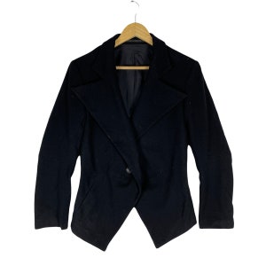 May include: A black blazer with a long, pointed collar and a single button closure. The blazer has a fitted silhouette and a slightly asymmetrical hem.