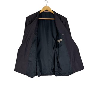 Op de afbeelding: Een donkergrijze blazer met een klassiek ontwerp, hangend aan een houten hanger. De blazer is open en onthult een zwarte binnenvoering en zakken. Het label "Y's" is zichtbaar.