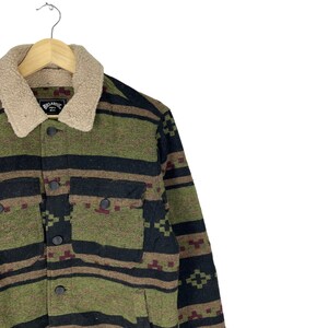 May include: A green, black and brown patterned jacket with a sherpa collar. The jacket has a button closure and a patch pocket on the left chest. The label on the jacket reads "Billabong".