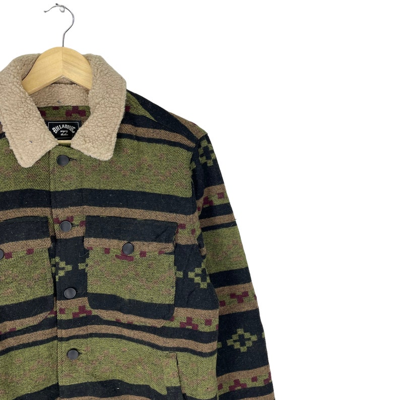 May include: A green, black and brown patterned jacket with a sherpa collar. The jacket has a button closure and a patch pocket on the left chest. The label on the jacket reads "Billabong".
