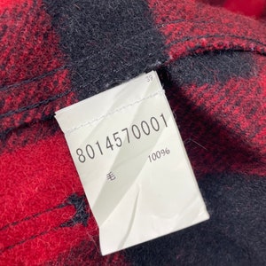 Op de afbeelding: Wit etiket met zwarte tekst. Het etiket zegt "8014570001" en "100%  羊".