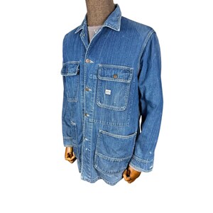 May include: A blue denim jacket with multiple pockets, including two chest pockets and two lower pockets. The jacket has a button-up front, a collar, and long sleeves. The denim has a worn appearance.