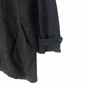 May include: A dark gray tweed coat with a button on the cuff. The coat has a textured fabric and a relaxed fit.