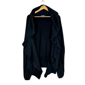 May include: Black hooded cardigan with a ruffled front and a long, asymmetrical hem. The cardigan is made of a soft, comfortable fabric and has a relaxed fit.