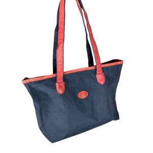 May include: A black nylon tote bag with red leather trim and handles. The bag has a zipper closure and a small leather logo patch on the front.