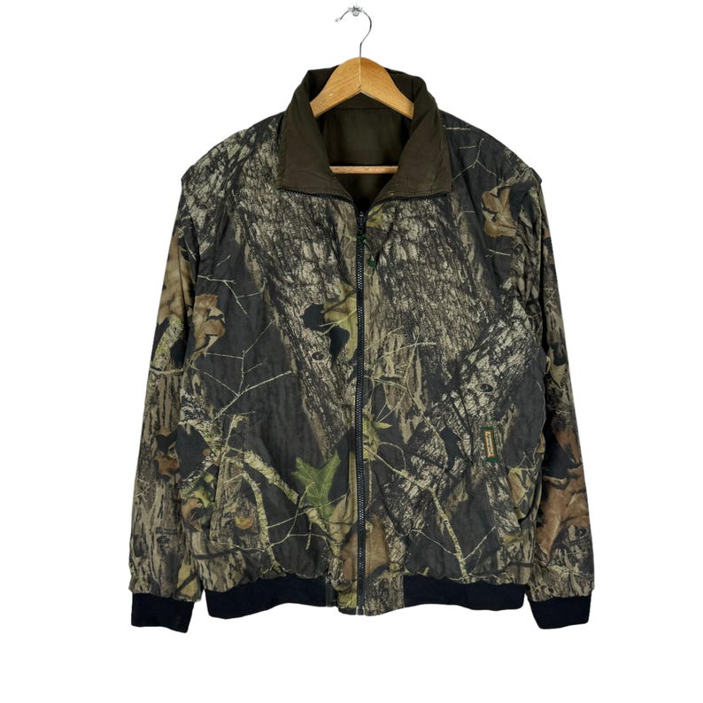 May include: A camouflage-patterned jacket with a zip closure and black trim. The jacket is made of a lightweight fabric and has a quilted lining.