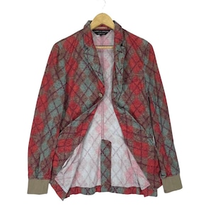 May include: A red, green, and brown plaid blazer with a single-button closure. The blazer has long sleeves with brown cuffs and is hanging on a wooden hanger. The interior lining is a lighter plaid pattern.