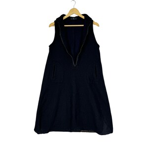 K&ouml;nnte beinhalten: Ein schwarzes &auml;rmelloses Kleid mit einem Rei&szlig;verschluss vorne und zwei Taschen. Das Kleid hat einen leicht ausgestellten Rock.