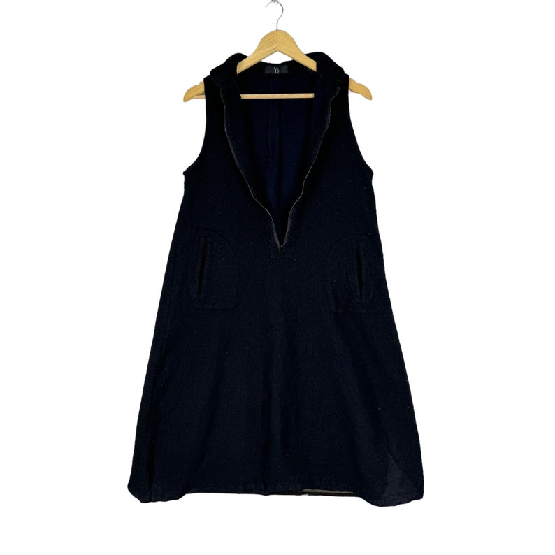 K&ouml;nnte beinhalten: Ein schwarzes &auml;rmelloses Kleid mit einem Rei&szlig;verschluss vorne und zwei Taschen. Das Kleid hat einen leicht ausgestellten Rock.