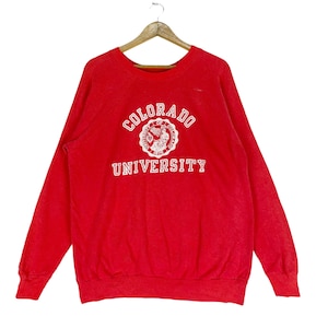 Może przedstawiać: Czerwona bluza z białym logo Uniwersytetu Kolorado i napisem "COLORADO UNIVERSITY" nadrukowanym z przodu.