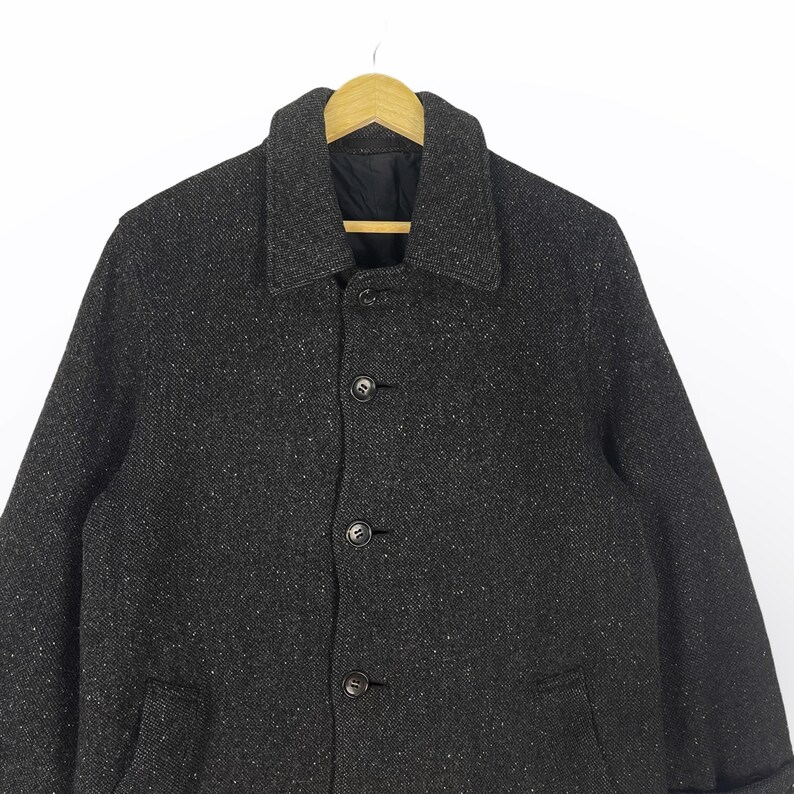 May include: A dark gray tweed jacket with a button closure and a collared neckline.