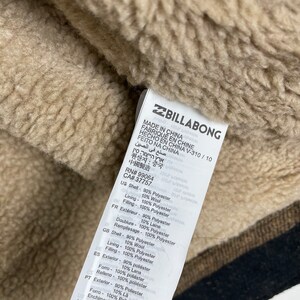 May include: A brown and beige Billabong jacket label with the text "Made in China" and other details about the jacket's materials and manufacturing. The label also includes the RN# 99064 and CA# 37757.