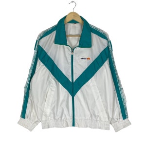 May include: White and teal blue windbreaker jacket with a zipper closure and the word "ellesse" printed on the front. The jacket has a teal blue chevron design on the front and the word "ellesse" printed on the sleeves.
