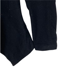 May include: Close-up of the black fabric sleeve of a garment. The fabric is smooth and has a slight sheen.