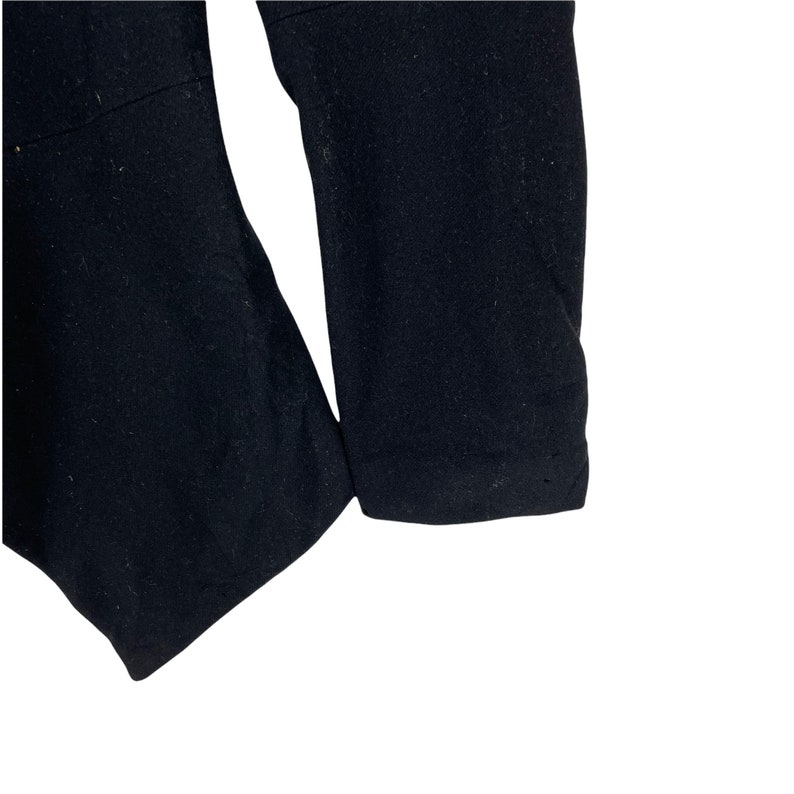 May include: Close-up of the black fabric sleeve of a garment. The fabric is smooth and has a slight sheen.
