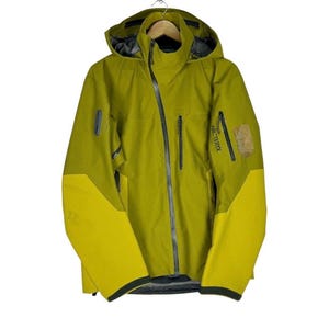 May include: A yellow and green hooded jacket with a zipper closure and the word "ARC'TERYX" on the right sleeve.
