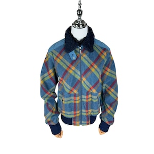 May include: A blue plaid jacket with a navy blue collar and cuffs. The jacket features a zipper closure and a pattern of red, yellow, and green lines. The jacket is displayed on a mannequin.