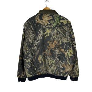 May include: A green, brown and black camouflage jacket with a zip fastening and a black ribbed collar.