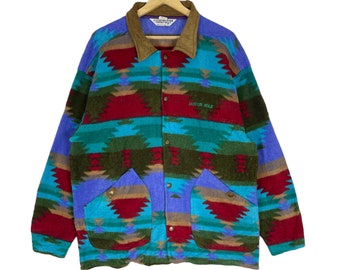 May include: A blue, green, red, and brown patterned fleece jacket with a suede collar and two large pockets. The jacket has a button closure and the text "Jackson Hole" is embroidered on the front.