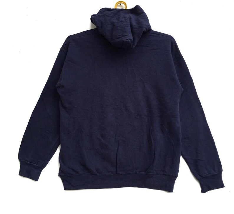 K&ouml;nnte beinhalten: Ein marineblauer Kapuzenpullover mit einer K&auml;ngurutasche. Der Pullover hat lange &Auml;rmel und einen gerippten Saum.