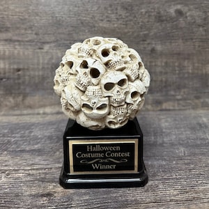 May include: A black and white skull trophy with the words "Halloween Costume Contest Winner" on the base.