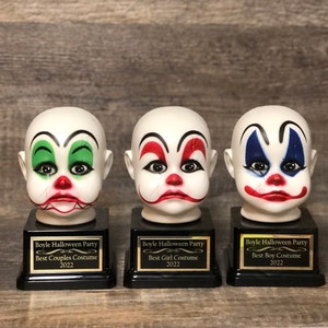 May include: Three white porcelain clown head trophies with black bases and gold lettering. The trophies are labelled "Boyle Halloween Party" with the categories "Best Couples Costume", "Best Girl Costume", and "Best Boy Costume".