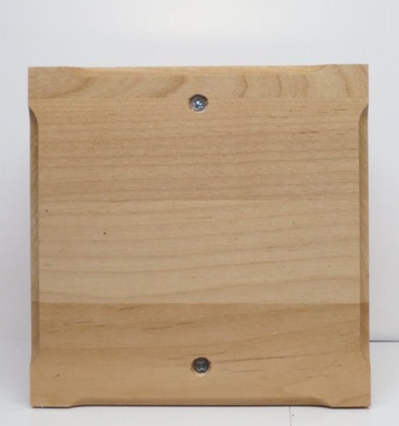 Puede incluir: Una placa de madera de color marr&oacute;n claro, simple, con dos tornillos plateados en el centro.