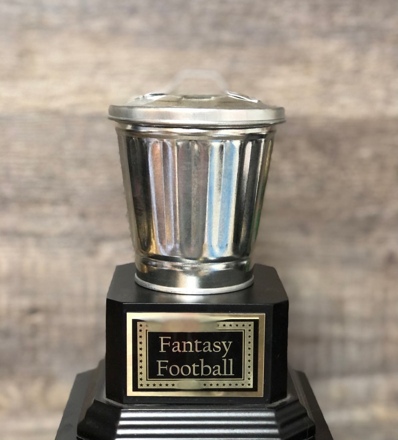 May include: A silver trash can trophy with a black base and a gold plaque that reads "Fantasy Football".