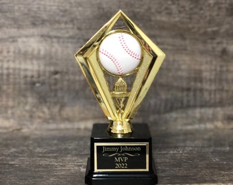 May include: Gold baseball trophy with a white baseball on top. The base of the trophy is black with a gold plaque that reads "Jimmy Johnson MVP 2022".