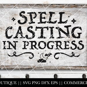 May include: A white wooden sign with black text that reads "SPELL CASTING IN PROGRESS". The sign has a crescent moon and bat design at the bottom.