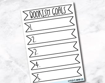 May include: A white sticker with the text "BOOKISH GOALS" at the top and bottom. The sticker has five horizontal banner-shaped sections numbered 1 through 5, designed for listing goals. The sticker is from cricket PAPER CO.