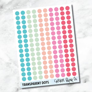 May include: A sheet of transparent dot stickers in various colors, including teal, mint green, peach, pink, and red. The text "TRANSPARENT DOTS" and "Cricket Paper Co." are printed at the bottom. The dots are arranged in vertical columns.