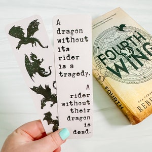 May include: Two light pink bookmarks with black dragon silhouettes and the quote: "A dragon without its rider is a tragedy. A rider without their dragon is dead." A book titled "Fourth Wing" is also visible.