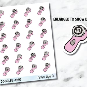 Könnte beinhalten: Blatt mit Aufklebern mit rosa und grauen Gesichtsreinigungsgeräten. Die Aufkleber haben einen schwarzen Umriss und einen kleinen grauen Knopf. Der Text "ENLARGED TO SHOW DETAIL" ist in Schwarz. Der Text "DOODLES - 060" und "Cricket Paper Co." sind ebenfalls sichtbar.