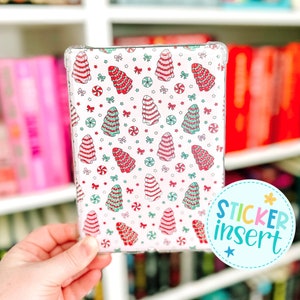 May include: Clear protective case featuring a repeating pattern of Christmas tree-shaped candies in red, green, and white on a white background. The design includes bows and candies. The text "STICKER INSERT" is on the bottom right.