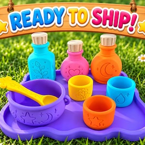 May include: A set of colorful silicone potion-making toys on a purple tray, including a purple cauldron with a yellow spoon, three small cups with embossed shapes, and three bottles with silver caps. The text READY TO SHIP is displayed above.