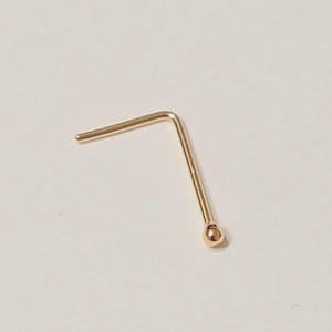 Könnte beinhalten: Ein goldfarbener Nasenstecker mit einem kleinen Kugelende und einem geraden Stab. Der Stecker ist rechtwinklig gebogen. Der Schmuck ist vor einem neutralen Hintergrund platziert.