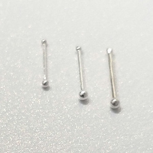 May include: Three silver nose rings with small ball ends. The rings are of different lengths.