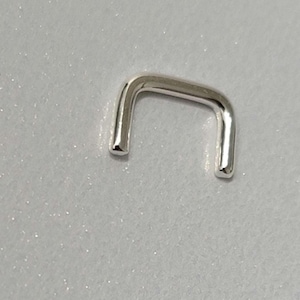 Puede incluir: Un aro para la nariz de plata con un diseño de aro. El aro está abierto por un lado y tiene un acabado liso y pulido.