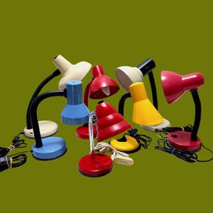 May include: A collection of six vintage desk lamps in various colors, including red, blue, yellow, white, and cream. The lamps have adjustable arms and shades.